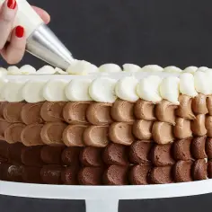 Dłoń z rękawem cukierniczym dekoruje tort, tworząc warstwy kremu. Oto jak zrobić krem do tortu!