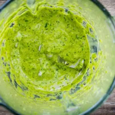 Zielone, kremowe pesto z awokado w kielichu blendera, gotowe do podania.
