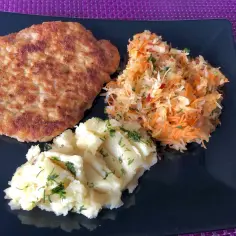 Schabowy z ziemniakami i surówką to świetny pomysł, co zrobic ze schabu na obiad. Pyszny, złocisty kotlet na talerzu.