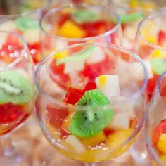 Kolorowe desery owocowe w kieliszkach, z kawałkami kiwi, mango i galaretki. Idealne pytanie: czy ananasa można zalać galaretką?