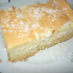 Pyszny sernik z wiórkami kokosowymi na wierzchu, podany na talerzu z kwiatowym wzorem.