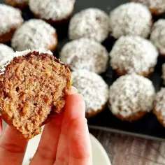 Pyszne muffinki z cukinią, oblane czekoladą i posypane wiórkami kokosowymi. Jedna muffinka jest przekrojona, ukazując wilgotne wnętrze.