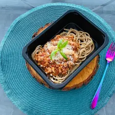 Pyszne spaghetti bolognese z makaronem pełnoziarnistym, posypane parmezanem i bazylią. Idealny wybór dla cateringu dietetycznego w Białej Podlaskiej.