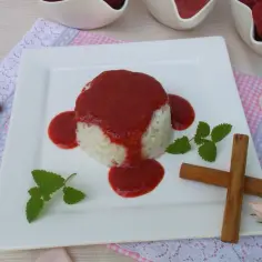 Pyszny ryż na mleku z truskawkami, udekorowany listkami mięty i laskami cynamonu. Idealny deser na letnie popołudnie.