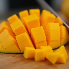 Pokrojony w kostkę mango owoc jak jeść. Soczyste, pomarańczowe kawałki na desce, gotowe do spożycia.