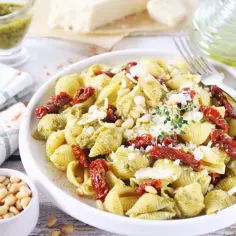 Pyszny makaron z pesto, suszonymi pomidorami i orzeszkami pinii, posypany parmezanem. Idealny na szybki obiad.
