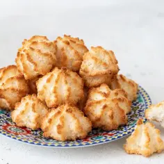 Stos puszystych kokosanek bez maki na kolorowym talerzu. Idealne na deser dla miłośników kokosa.