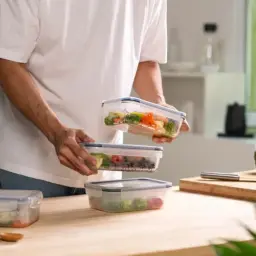 Przygotowanie posiłków do pojemników to pierwszy krok, jak otworzyć catering. Widać tu zdrowe jedzenie i świeże warzywa.