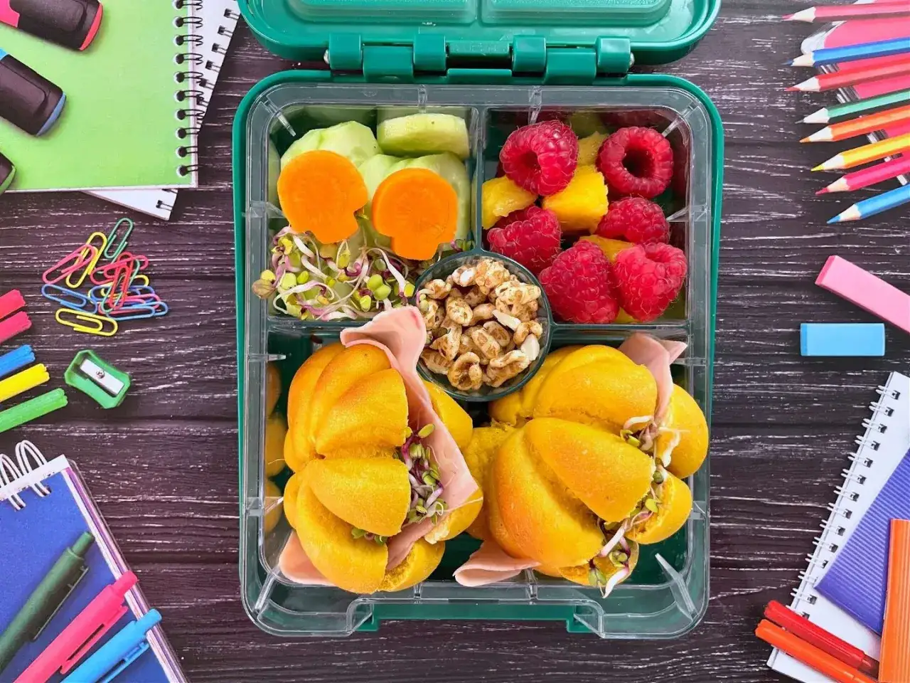 Kolorowy lunchbox z pomarańczowymi bułeczkami, kiełkami, malinami i innymi smakołykami. Idealne śniadania do przedszkola!