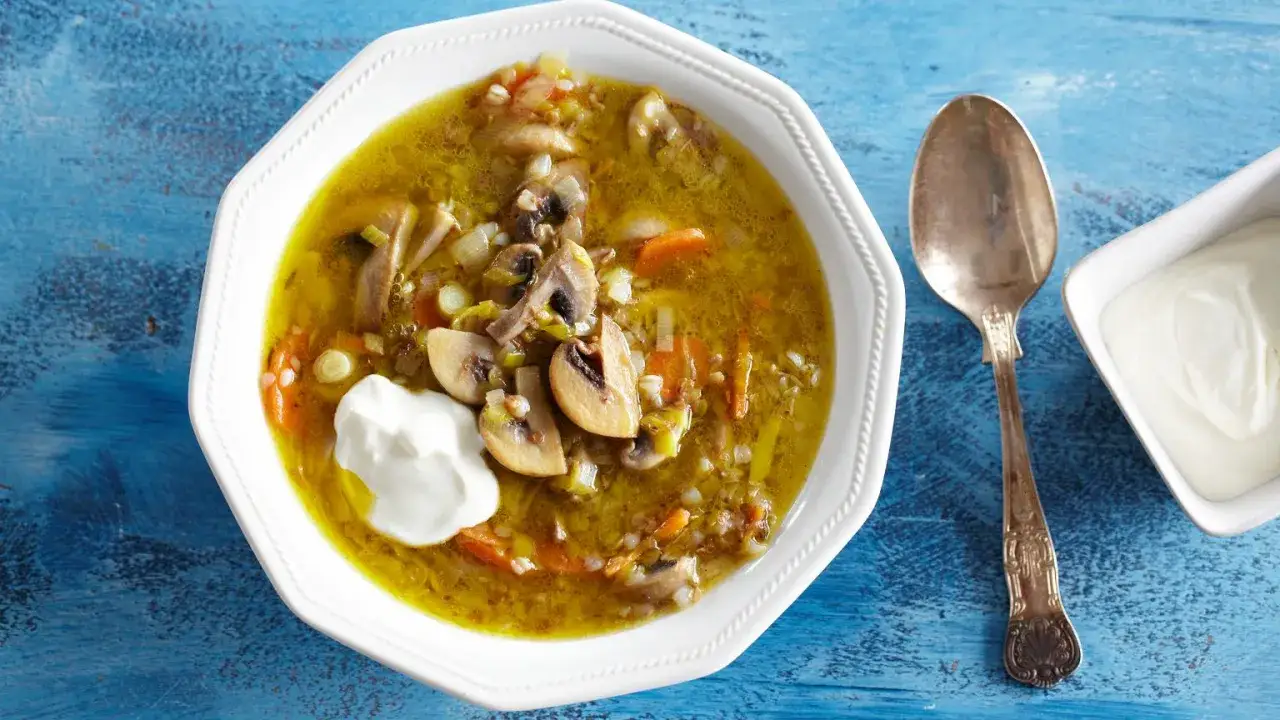 Aromatyczna zupa pieczarkowa z ziemniakami i kaszą, podana z kleksem śmietany.