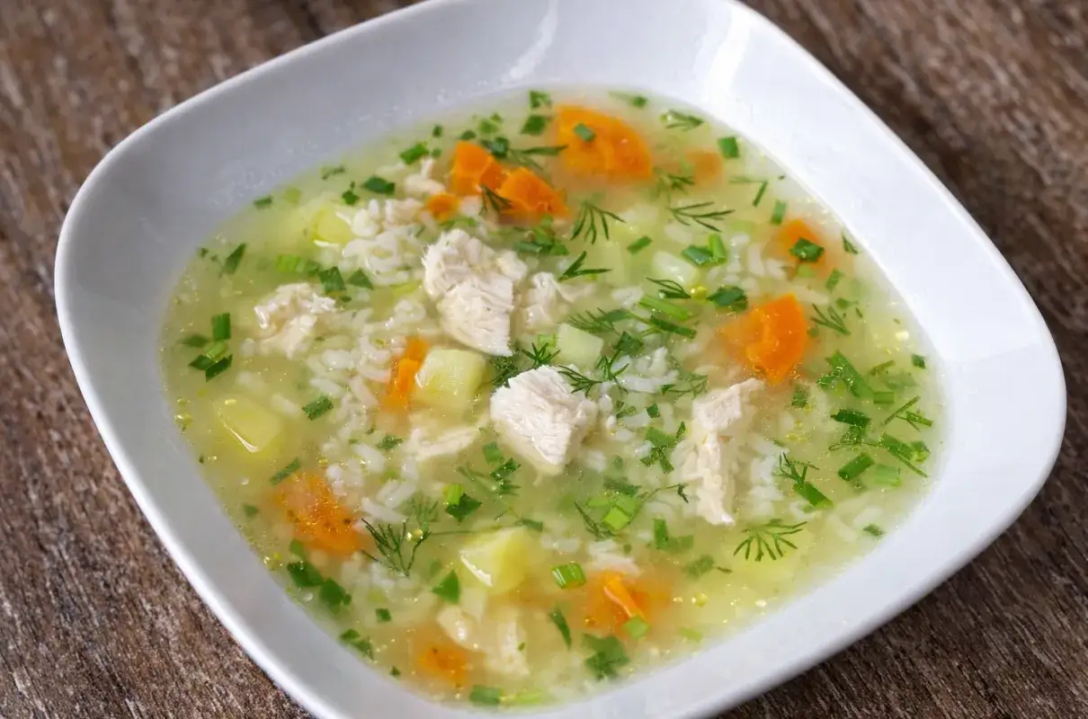 Aromatyczna zupa ryżowa z ziemniakami, kawałkami kurczaka, marchewką i zieloną pietruszką.