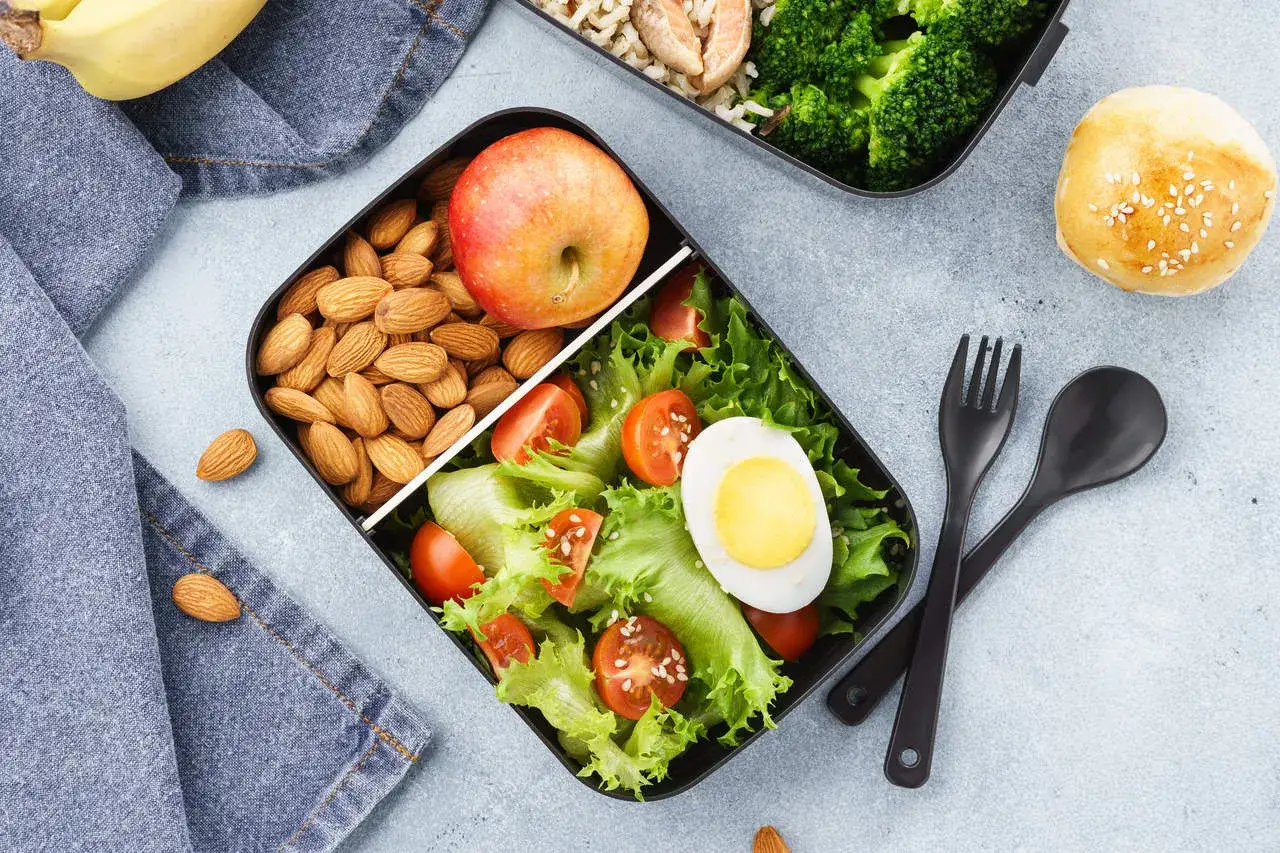 Zdrowy lunchbox: sałatka z jajkiem, pomidorkami i sałatą, migdały, jabłko. Idealne co do jedzenia do pracy.