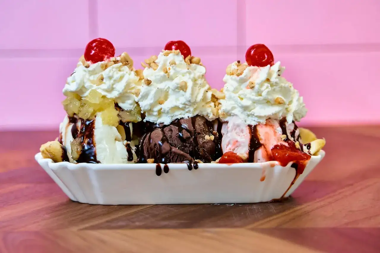 Pyszne lody z mrożonych bananów, polane czekoladą, z bitą śmietaną i wiśniami. Idealny deser na upalne dni.