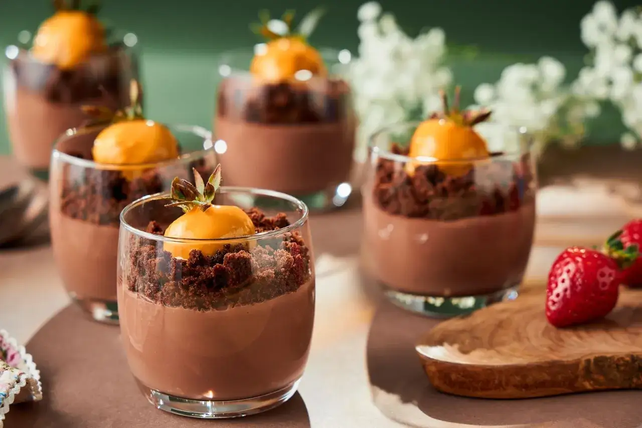 Pyszny deser czekoladowy w szklankach, idealny przepis na to, jak zrobić pudding czekoladowy. Udekorowany owocem i kruszonką.
