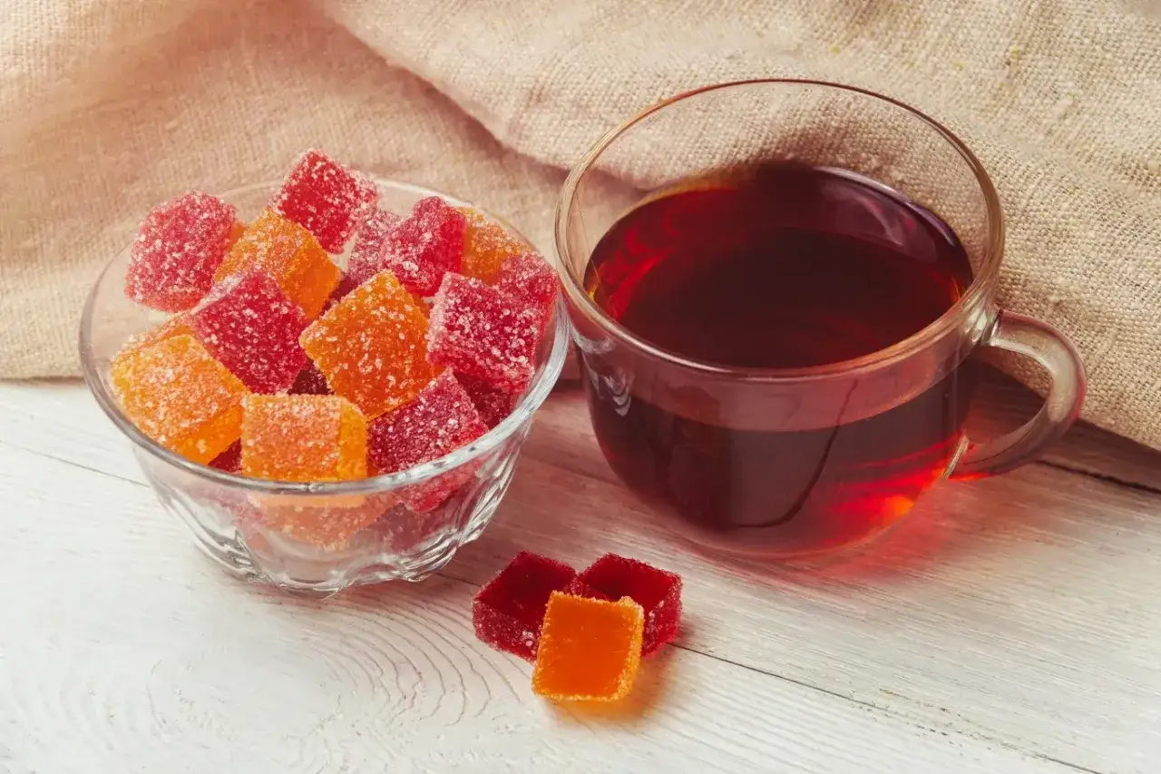 Cukierki galaretkowe w miseczce i obok kubek herbaty. Zastanawiasz się, ile kolagenu ma galaretka owocowa?