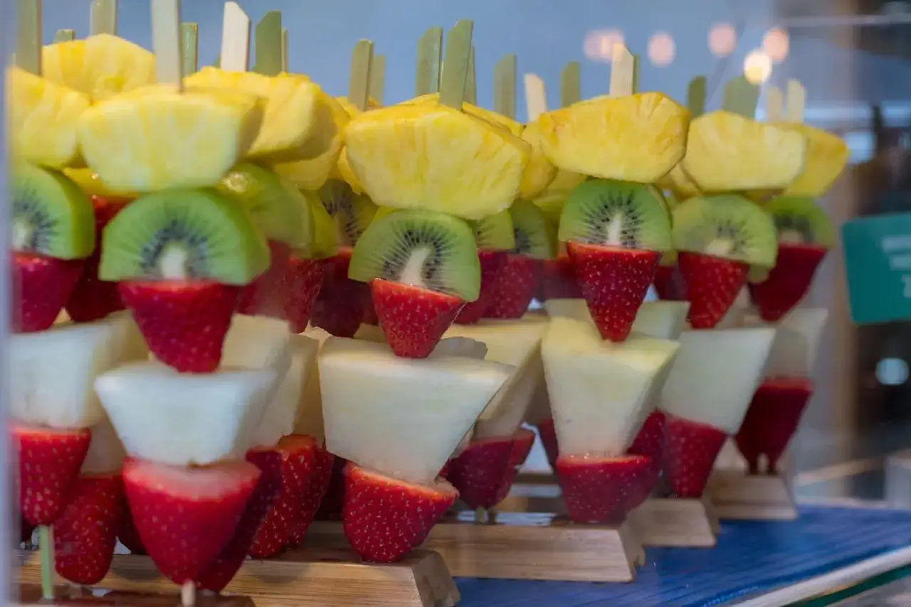 Kolorowe szaszłyki z owoców: ananas, kiwi, truskawki i melon. Idealny sposób, jak efektownie podać owoce na przyjęciu.