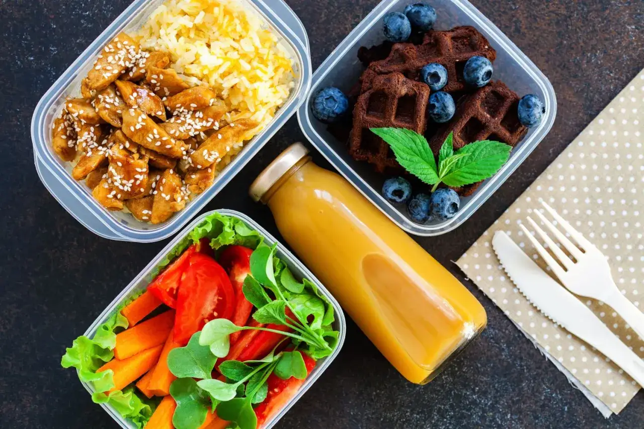 Gotowe lunchboxy do pracy: kurczak z ryżem, sałatka z warzywami, czekoladowe gofry z jagodami i sok. Idealne przepisy na zdrowy posiłek.