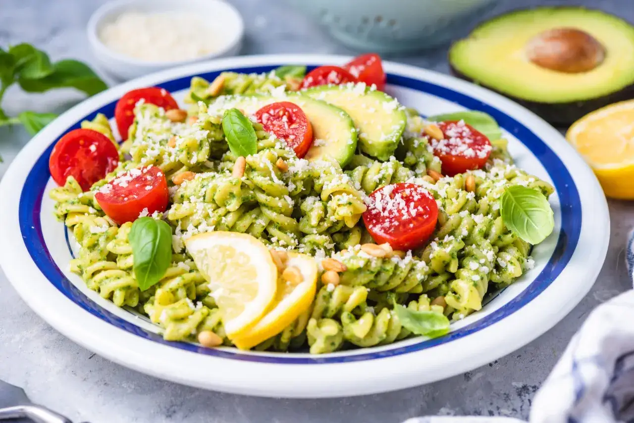 Pyszny makaron z kremowym pesto z awokado, pomidorkami koktajlowymi, orzeszkami pinii i parmezanem.