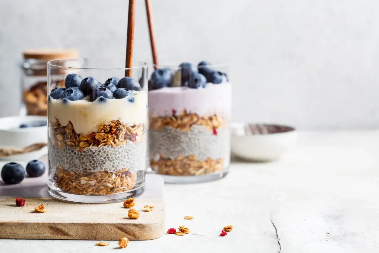 Pyszne desery z płatków owsianych: chia, granola i jagody w szklankach. Idealne na śniadanie lub przekąskę.